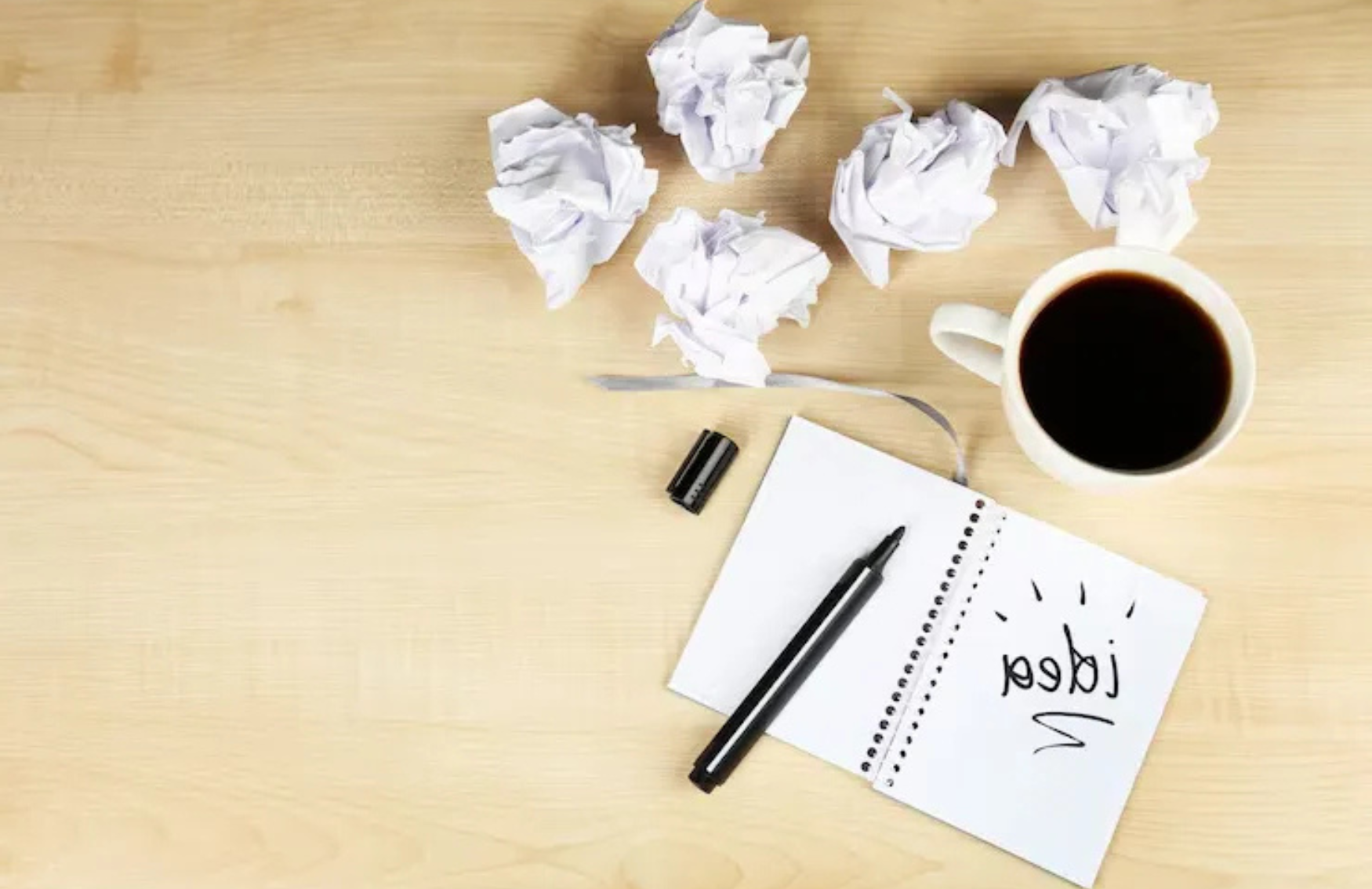 An iamge showing writing pad and so many papers folded and thrown aroun as wastage showing the copywriting tone impact