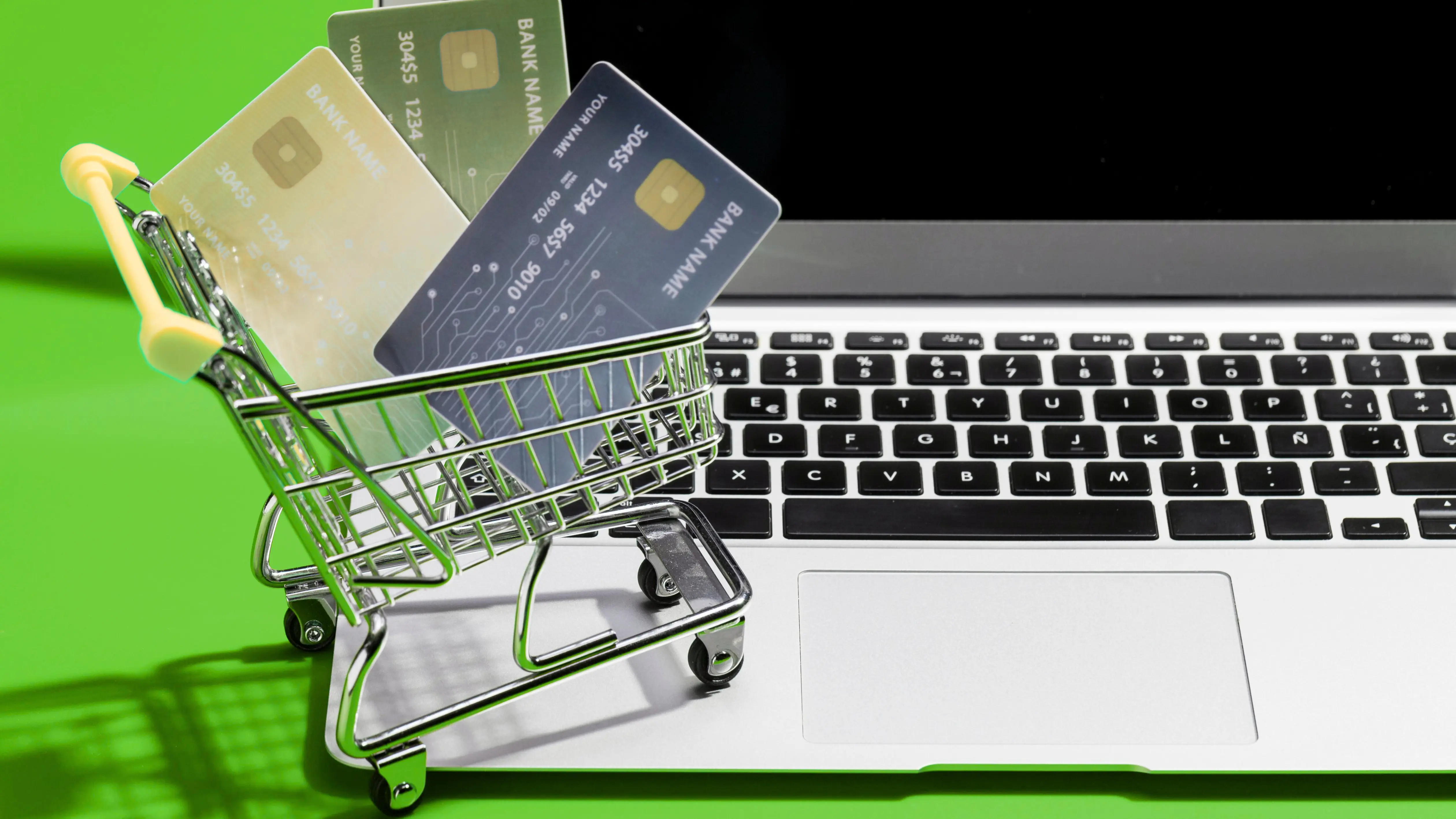 a mini cart with carts and a laptop to represnt the best shopify payemnet gateways there is green table sheet